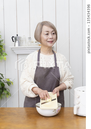 Senior woman making snack potato chips in an air fryer 135434396