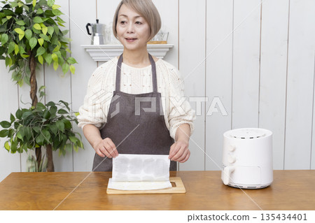 Senior woman making snack potato chips in an air fryer Senior woman making snack potato chips in an air fryer 135434401