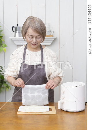 一位老年婦女用氣炸鍋製作薯片零食 135434403