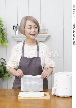 一位老年婦女用氣炸鍋製作薯片零食 135434405