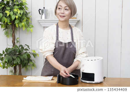 Senior woman making snack potato chips in an air fryer 135434409