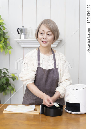Senior woman making snack potato chips in an air fryer 135434412