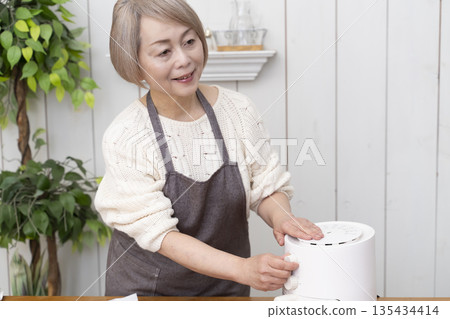 Senior woman making snack potato chips in an air fryer 135434414