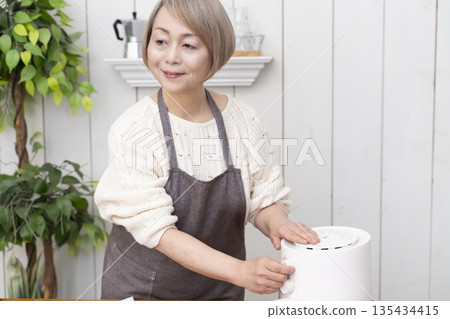 Senior woman making snack potato chips in an air fryer 135434415