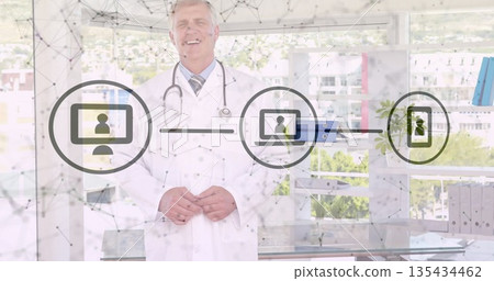 Standing male physician wearing lab coat and stethoscope at glass desk, with telemedicine overlay 135434462