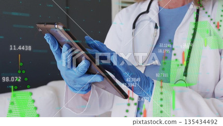 Analyzing doctor interacting with tablet in clinic, with stethoscope, gloves, digital overlays 135434492