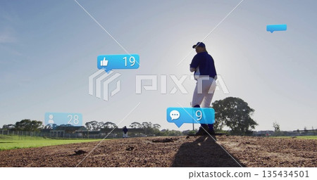 Throwing ball, baseball pitcher wearing navy jersey and cap on sunlit mound with social media icons 135434501