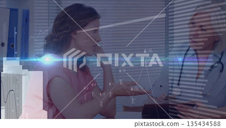 Patient and doctor in scrubs discussing symptoms at consultation desk, with digital charts Patient and doctor in scrubs discussing symptoms at consultation desk, with digital charts 135434588