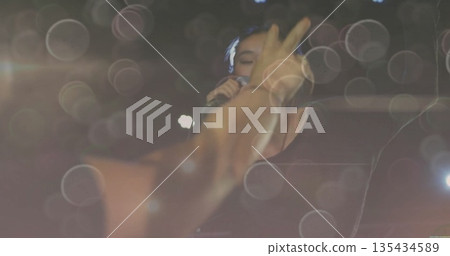 Chinese female singer singing on concert stage, with microphone, stage lights and bokeh reflections Chinese female singer singing on concert stage, with microphone, stage lights and bokeh reflections 135434589