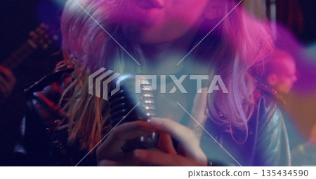 Singing singer wearing leather jacket gripping vintage mic onstage with electric guitar lights Singing singer wearing leather jacket gripping vintage mic onstage with electric guitar lights 135434590