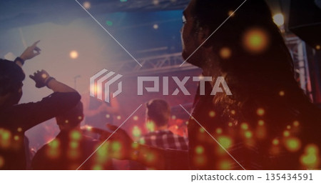 Long-haired man in plaid standing amid crowd at music venue, facing stage with fog, copy space 135434591