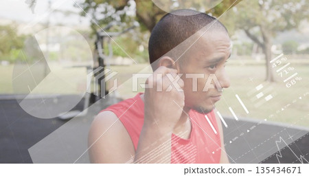 Preparing man in red shirt viewing data overlays near pull-up bars in city park, holding earbud Preparing man in red shirt viewing data overlays near pull-up bars in city park, holding earbud 135434671