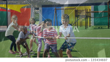 Pulling group of six children playing tug-of-war on synthetic turf field, with thick white rope Pulling group of six children playing tug-of-war on synthetic turf field, with thick white rope 135434697