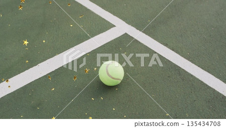 Resting tennis ball on outdoor tennis court near white lines, with gold star confetti, copy space Resting tennis ball on outdoor tennis court near white lines, with gold star confetti, copy space 135434708