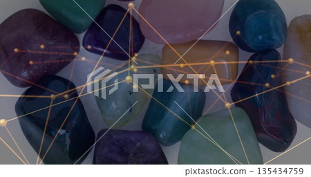 Displaying polished multicolored gemstones arranged on white tabletop, with golden network overlay 135434759