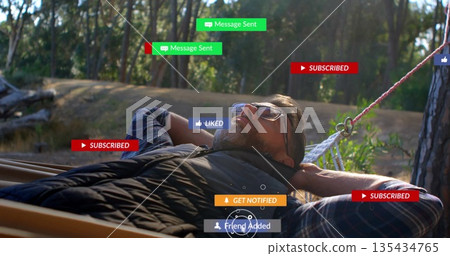 Relaxing man wearing puffer vest over plaid shirt in pine rope hammock, with floating UI badges Relaxing man wearing puffer vest over plaid shirt in pine rope hammock, with floating UI badges 135434765