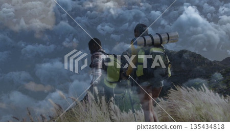 Climbing hikers ascending grassy mountain slope, with backpacks trekking poles sleeping pads Climbing hikers ascending grassy mountain slope, with backpacks trekking poles sleeping pads 135434818