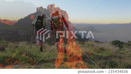 Walking hiking couple climbing mountain slope at sunrise, with backpacks, poles, boots, flames 135434836
