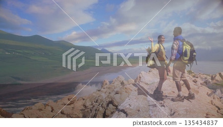 Waving hikers overlooking beach on headland, with neon green backpacks and hiking boots, copy space Waving hikers overlooking beach on headland, with neon green backpacks and hiking boots, copy space 135434837