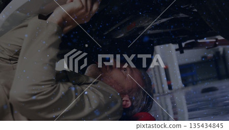 Reaching mechanic wearing tan uniform fixing vehicle undercarriage in auto workshop, with wrench 135434845