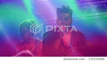 Performing lead vocalist holding microphone on stage in music club, with bassist and spotlights 135434890
