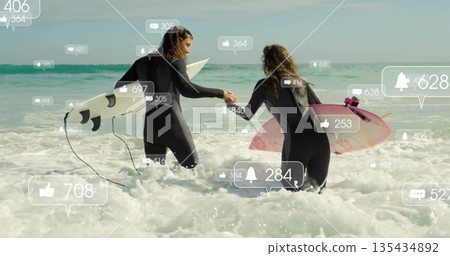 Walking wetsuit surfers carrying white and pink surfboards entering beach surf, with social icons Walking wetsuit surfers carrying white and pink surfboards entering beach surf, with social icons 135434892