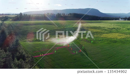Spraying center-pivot sprinkler arm high-pressure nozzle misting crops on rural farmland, water arc 135434902
