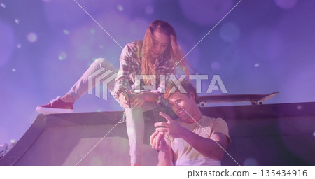 woman in plaid shirt and man in shorts examining smartphone on metal skate ramp, with skateboard woman in plaid shirt and man in shorts examining smartphone on metal skate ramp, with skateboard 135434916
