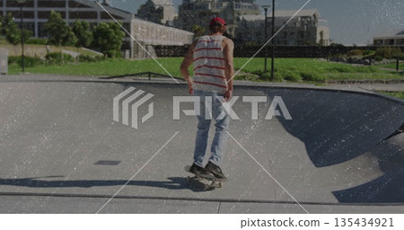 Skateboarding rider wearing red cap and tank top inside concrete bowl near lamppost Skateboarding rider wearing red cap and tank top inside concrete bowl near lamppost 135434921