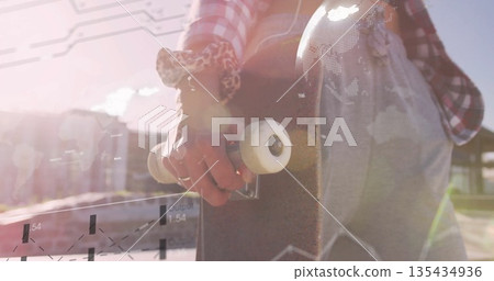 Skater holding skateboard in skate park, wearing red plaid, cutoffs with leopard-print wrist fabric 135434936