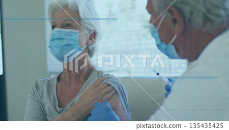 Sitting woman wearing mask receiving vaccine injection at clinic, with syringe, blinds, copy space Sitting woman wearing mask receiving vaccine injection at clinic, with syringe, blinds, copy space 135435425