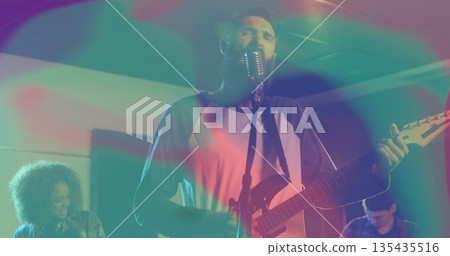 Performing bearded vocalist and guitarist strumming guitar singing on small stage, retro microphone 135435516