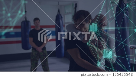 Demonstrating instructor applying hold on student in martial arts dojo with punching bags and mats Demonstrating instructor applying hold on student in martial arts dojo with punching bags and mats 135435548