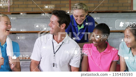 Smiling coach and athletes in colorful polos chatting on gym bleachers, with whistle, notifications Smiling coach and athletes in colorful polos chatting on gym bleachers, with whistle, notifications 135435593