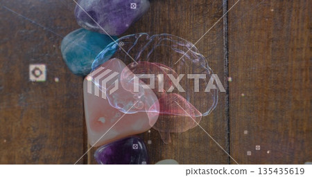 Displaying holographic brain model projecting over wooden tabletop, with gemstones and AR icons 135435619