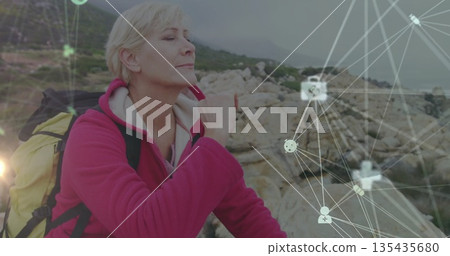 Inhaling woman wearing pink jacket carrying yellow-black backpack on rocky shore, network graphics 135435680