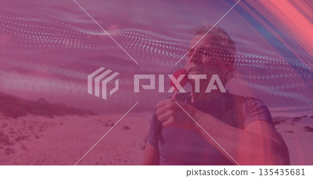 Hiker in blue shirt drinking from red bottle on sandy beach, with dark backpack, copy space Hiker in blue shirt drinking from red bottle on sandy beach, with dark backpack, copy space 135435681