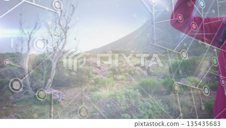 Woman shading eyes and surveying hillside scrubland in red jacket with network overlay, copy space 135435683