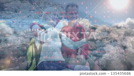 Smiling hiking couple holding smartphone with yellow and gray backpacks on rocky hill, code overlay Smiling hiking couple holding smartphone with yellow and gray backpacks on rocky hill, code overlay 135435686