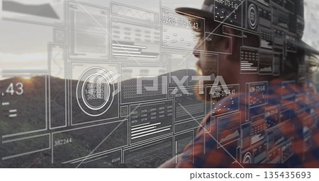 Standing man wearing safety helmet, plaid shirt analyzing AR data panels on hillside, copy space 135435693