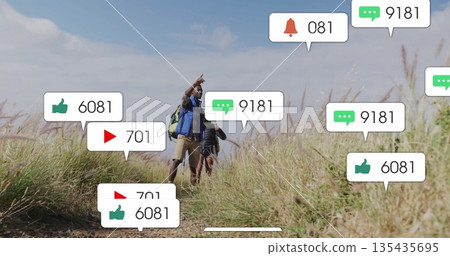 Hiking couple wearing backpacks, boots, cap on dirt trail flanked by golden grasses, pointing ahead Hiking couple wearing backpacks, boots, cap on dirt trail flanked by golden grasses, pointing ahead 135435695