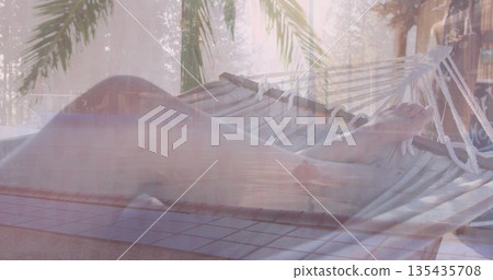 Lounging adult female wearing bikini relaxing in rope hammock over pool deck, with palm fronds Lounging adult female wearing bikini relaxing in rope hammock over pool deck, with palm fronds 135435708