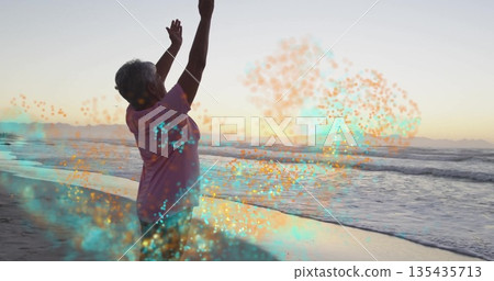 Raising arms woman in pink T-shirt standing on sunset beach with waves, particle effect, copy space Raising arms woman in pink T-shirt standing on sunset beach with waves, particle effect, copy space 135435713