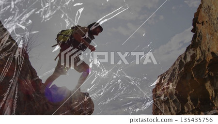 Stepping male hiker crossing narrow canyon gap at cliff, with backpack cap hiking boots, copy space 135435756