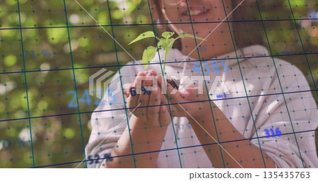 Showing Chinese schoolgirl cradling green seedling plant in greenhouse, with digital data overlay Showing Chinese schoolgirl cradling green seedling plant in greenhouse, with digital data overlay 135435763