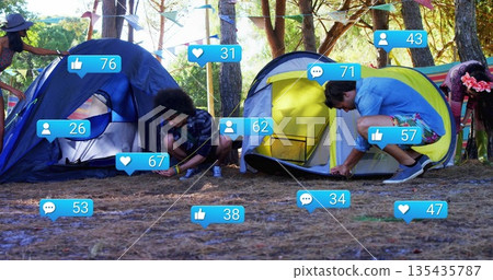 Group of friends assembling blue and yellow dome tents in pine forest, with social media icons 135435787