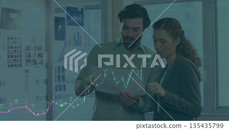 Reviewing colleagues in green shirt and blazer studying printed chart with hologram in meeting room Reviewing colleagues in green shirt and blazer studying printed chart with hologram in meeting room 135435799