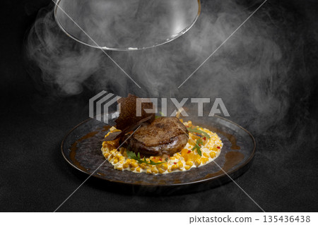 Duck leg with risotto, pumpkin and herbs on a dark background Duck leg with risotto, pumpkin and herbs on a dark background 135436438
