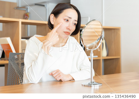 一位女性對著鏡子,擔心自己的皮膚狀況 一位女性對著鏡子,擔心自己的皮膚狀況 135436490