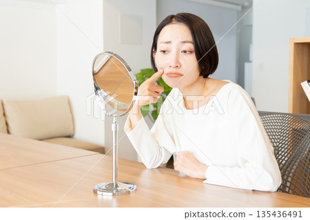 A woman who looks in the mirror and worries about her skin condition A woman who looks in the mirror and worries about her skin condition 135436491
